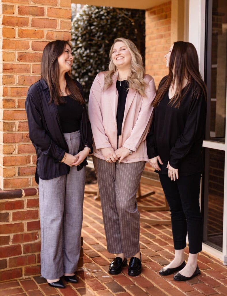 Three female staff posing outside Bates Family Orthodontics